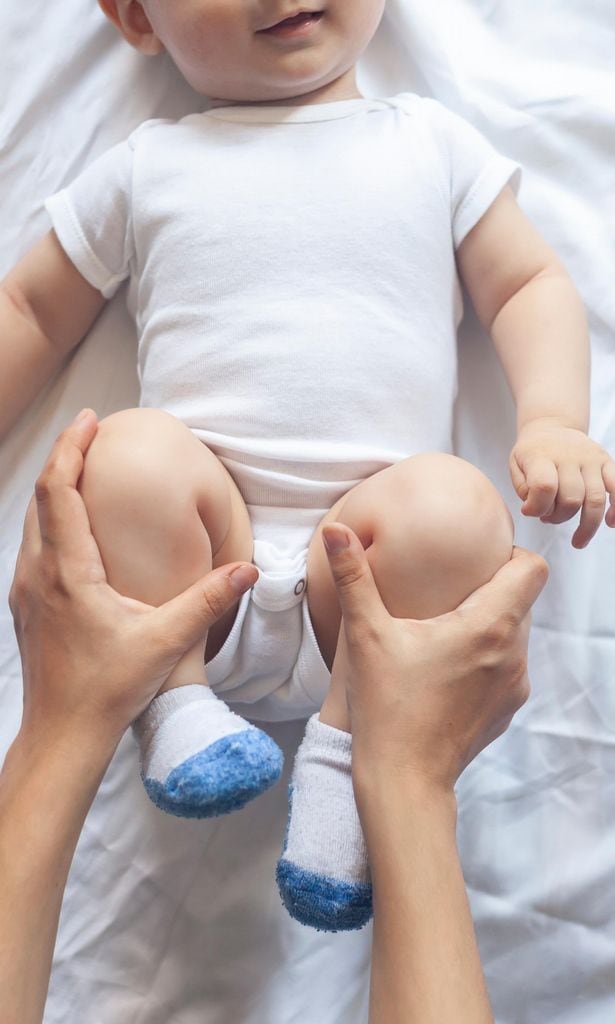 Madre haciendo movimientos en las piernas de su bebé para mejorar tránsito intestinal