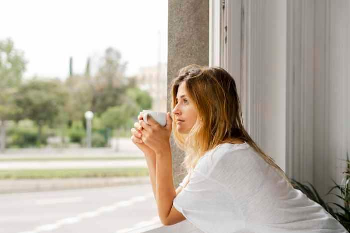 mujer tomando un café mirando por la ventana