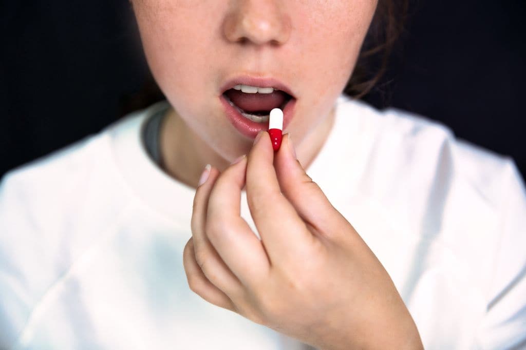 Adolescente tomando una pastilla