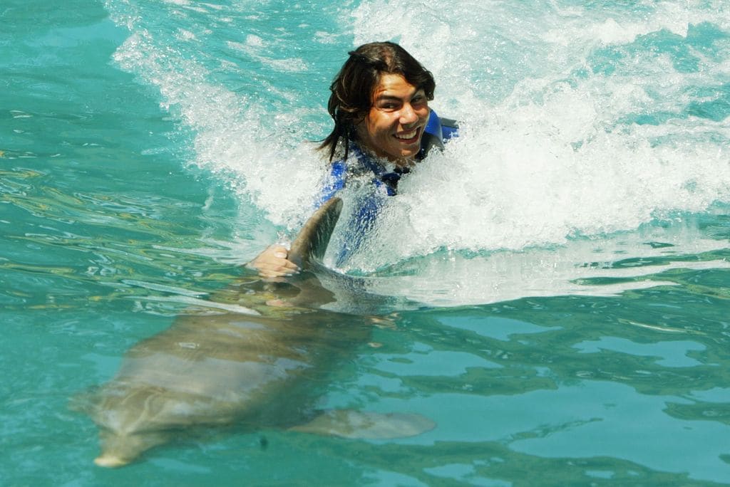 MIAMI, FLORIDA - MARCH 23:  Rafael Nadal of Spain rides a dolphin at the Miami Seaquarium during The Nasdaq 100 on March 23, 2004 in Miami, Florida. (Photo by Al Bello/Getty Images)