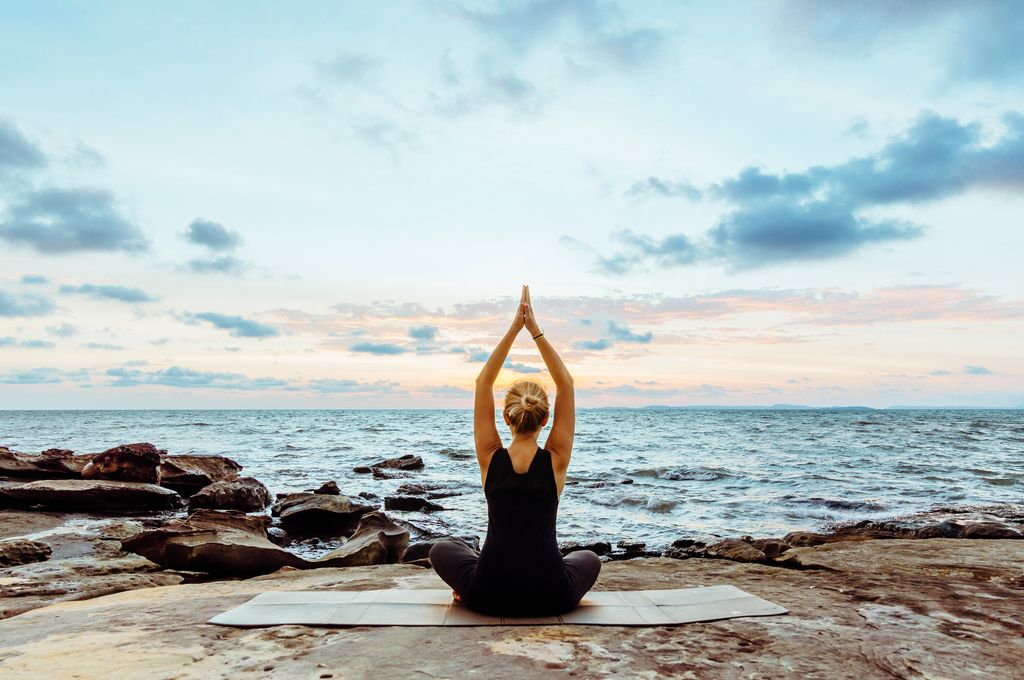 mujer haciendo yoga frente al mar