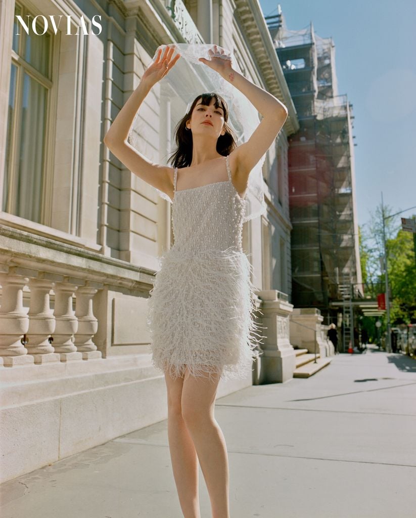 Luciendo como toda una runaway bride, Cristina, la top model protagonista de esta historia nupcial, deslumbra con un espectacular vestido corto de plumas de Nadine Merabi, tacones con perlas de Dolce Vita, y un encantador tocado con velo de East Village Hats.