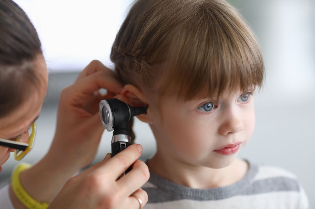 Niña en el médico mientras le examinan los oídos