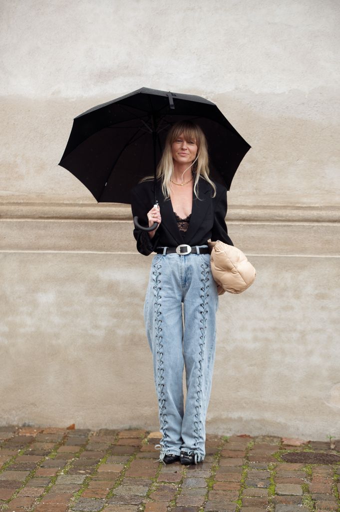 Jeanette Madsen lleva vaqueros azules, un top negro y una chaqueta negra, y un bolso beige fuera de The Garment durante la Semana de la Moda de Copenhague Primavera/Verano 2024 el 9 de agosto de 2023 en Copenhague, Dinamarca.