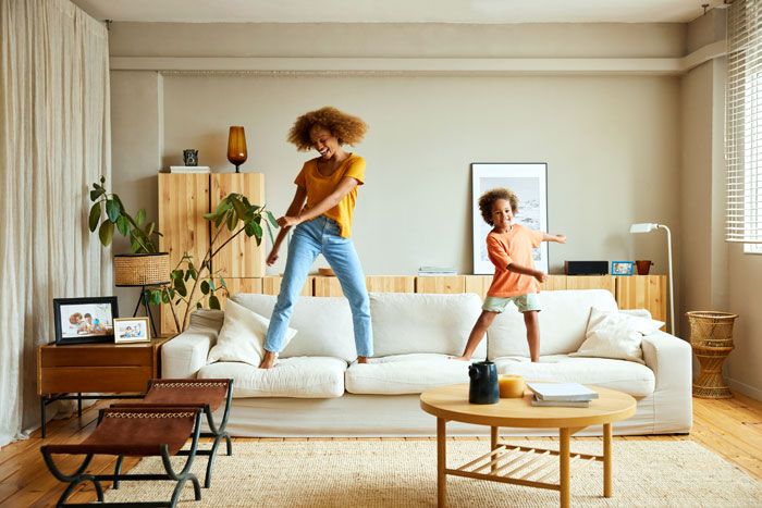 madre e hija felices bailando sobre el sofá