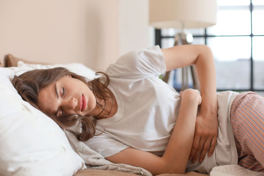 mujer enferma con dolor de estómago en la cama