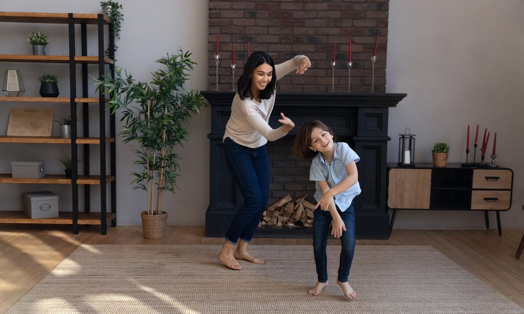 active asian babysitter and little boy dancing in living room