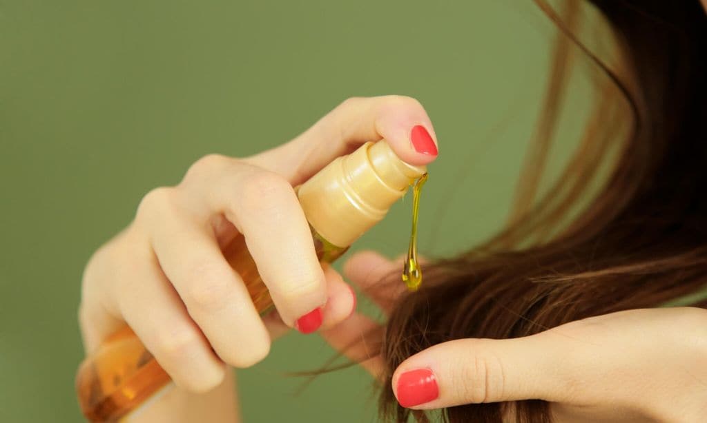 mujer aplicando aceite en las puntas del cabello