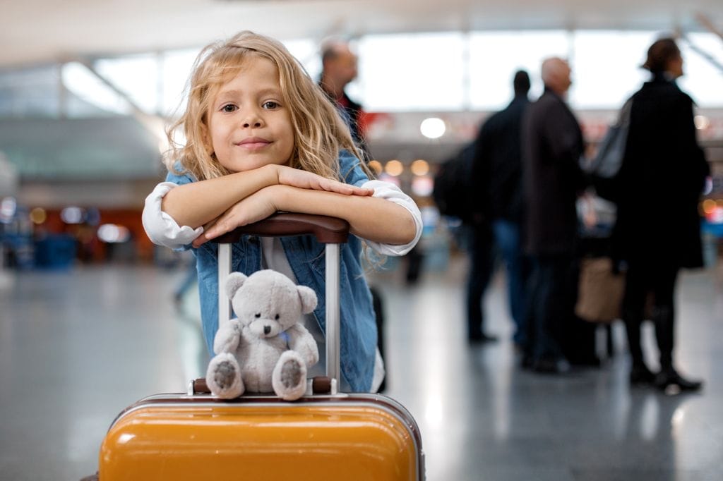 Niña con maleta dispuesta para viajar en contexto de custodia compartida