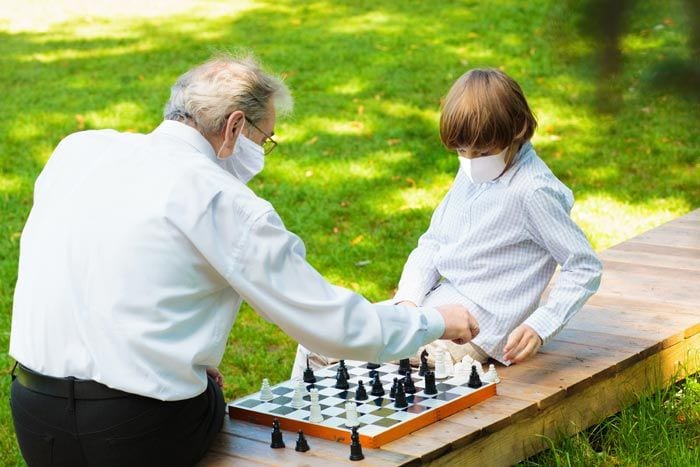 abuela y nieto jugando al ajedrez con mascarilla