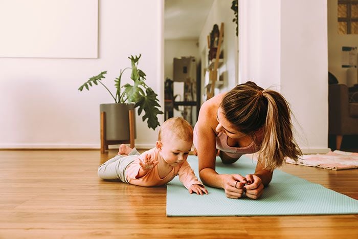 mujer entrenando con su bebé en casa