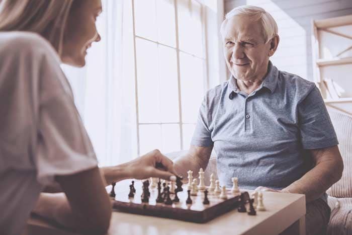 anciano y chica joven jugando al ajedrez