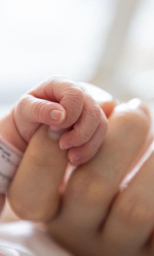 Mano de bebé agarrando dedo de su mamá