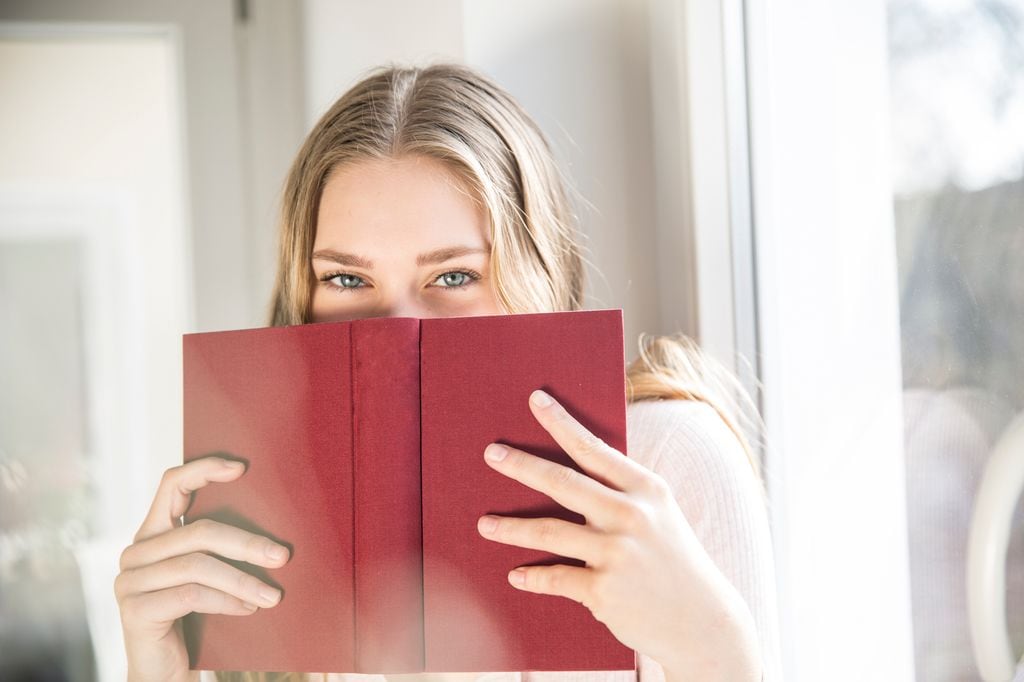 Mujer escondiendose tras un libro