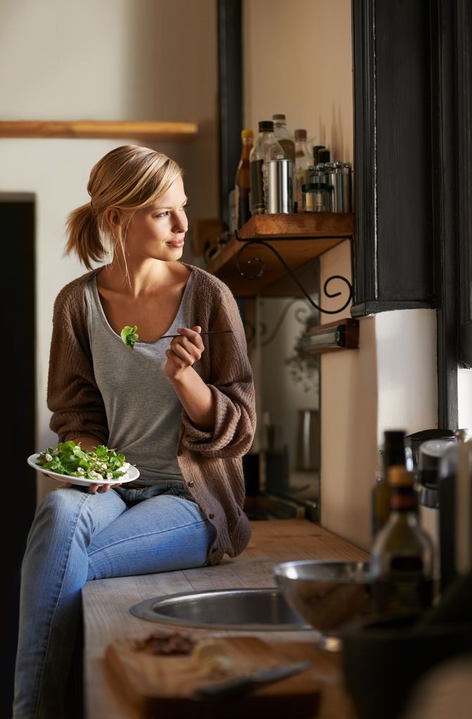 mujer comiendo ensalada en la cocina de casa