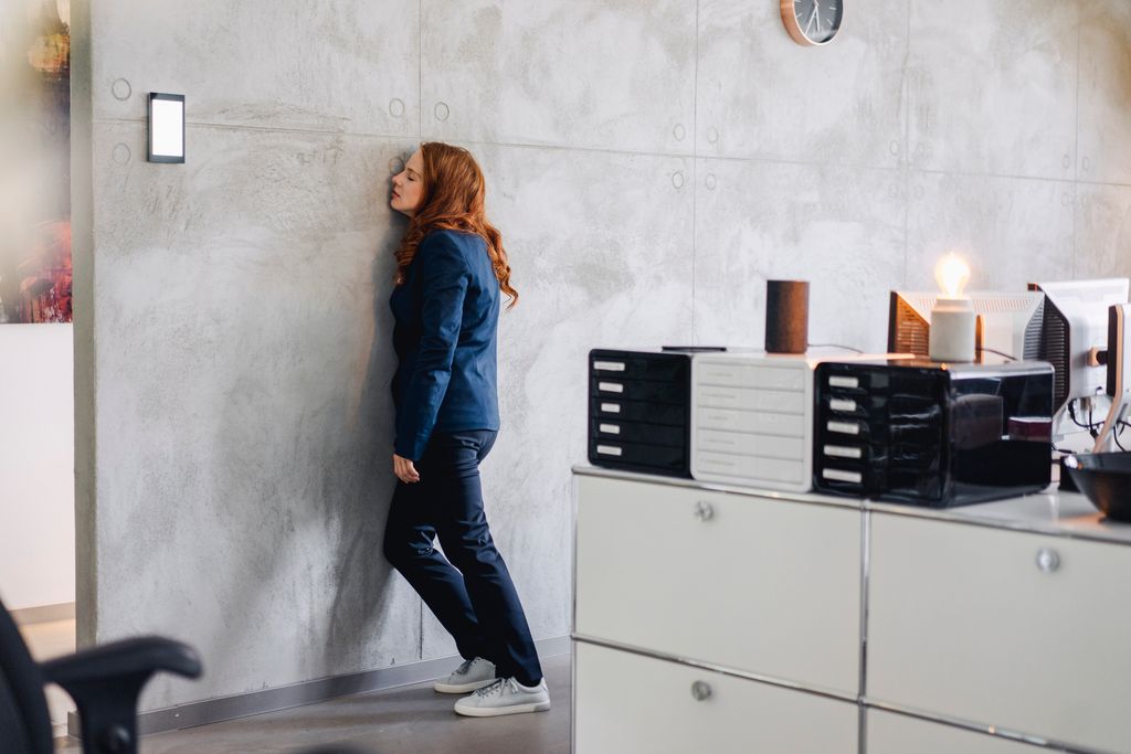 mujer cansada apoyando su cabeza en la pared