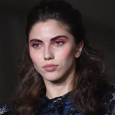 modelo de cabello ondulado con glosst lips y sombras de ojos en rojo