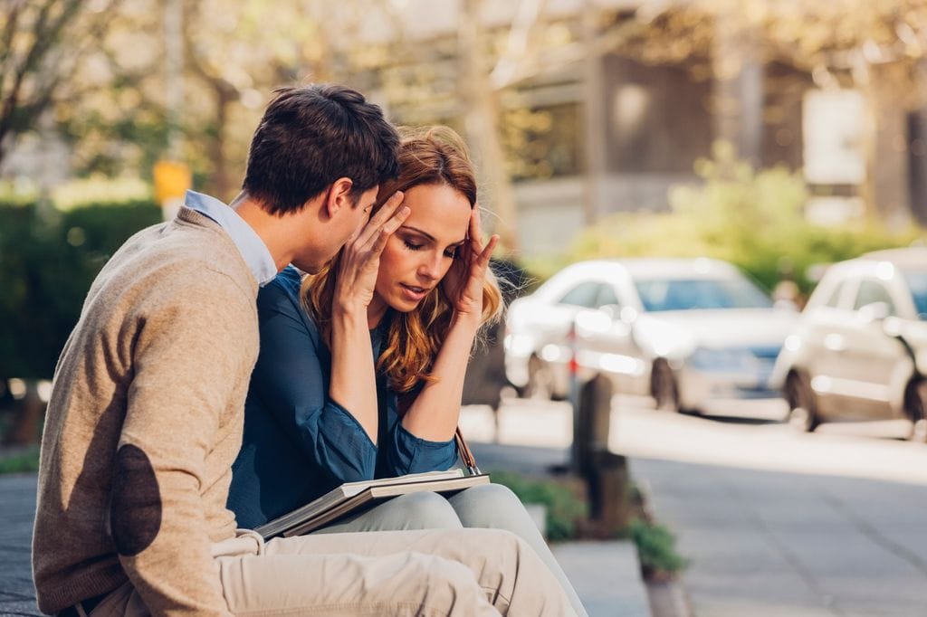 pareja en un banco discutiendo. La chica está preocupada