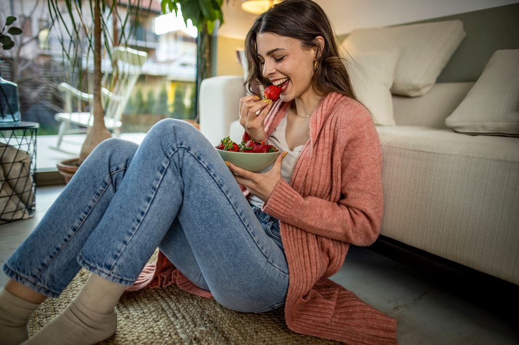 mujer sentada en el suelo, comiendo fresas