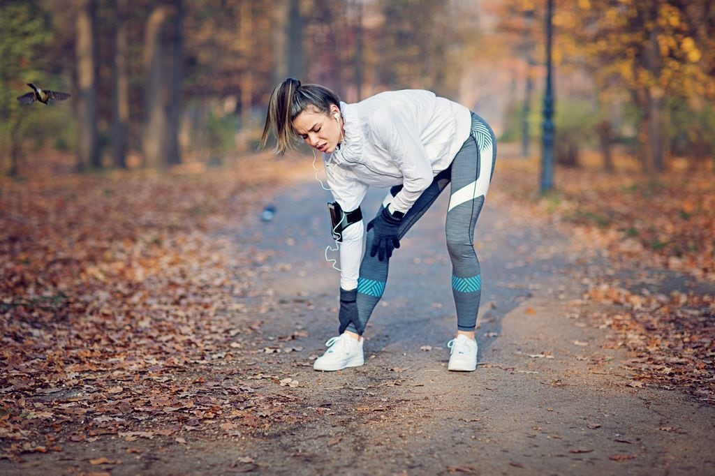 mujer joven haciendo deporte al aire libre con dolor en el tobillo