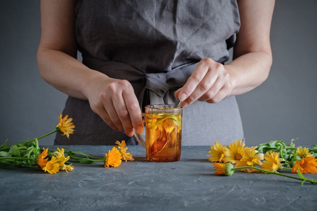 mujer haciendo un té de caléndula