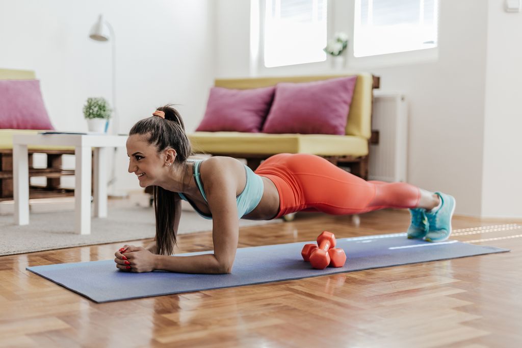 mujer joven haciendo planchas en casa