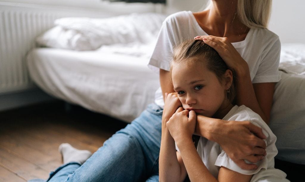 ni a triste abrazada a su mam sentadas las dos en el suelo de un dormitorio