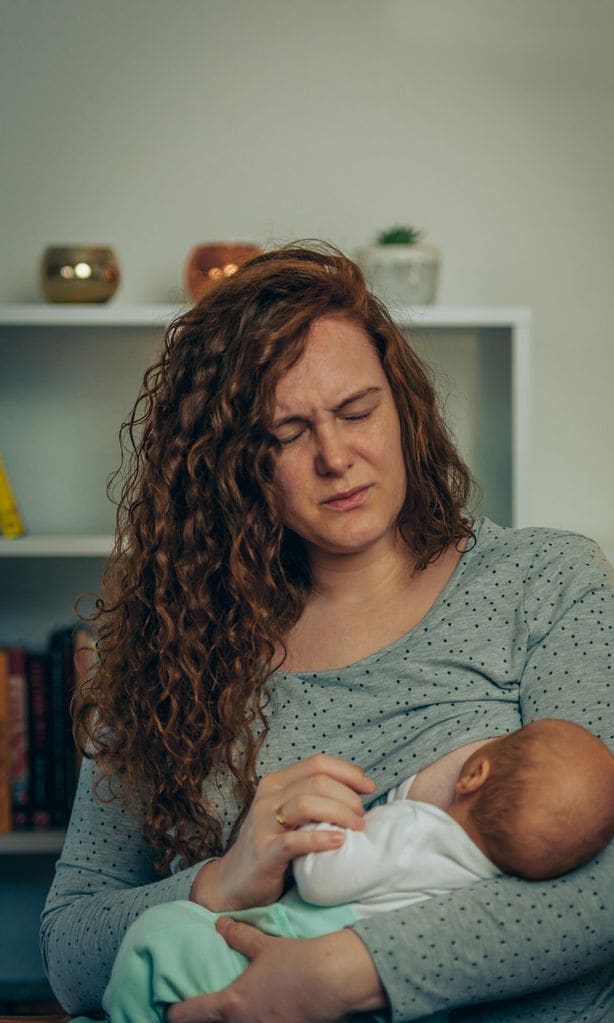 Mamá con dolor mientras da el pecho a su bebé