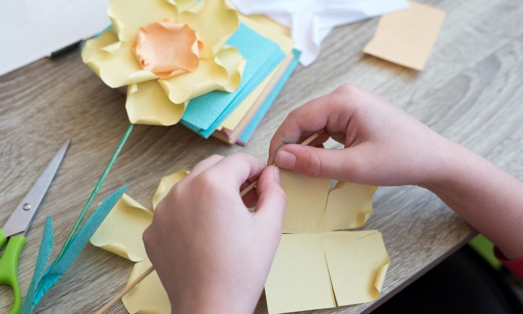 boy creating paper flower for mom mother day diy on quarantine or online education concept soft focus