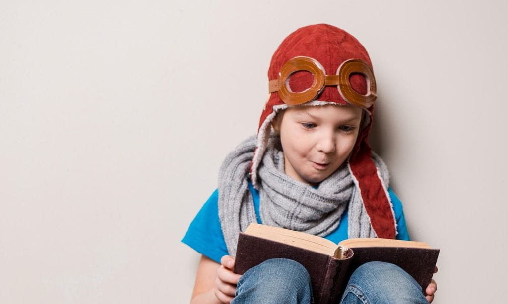 child reading a book in a traveling outfit