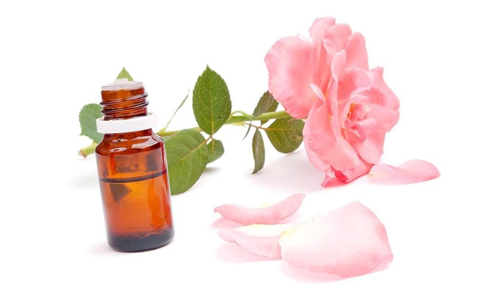 los mejores aceites faciales aceite de rosas junto a una flor y sus p talos al lado