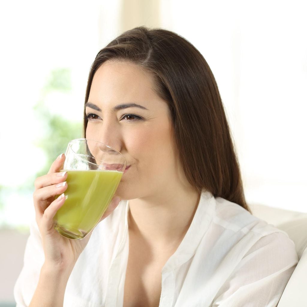 Joven de cabello liso, tomando jugo verde