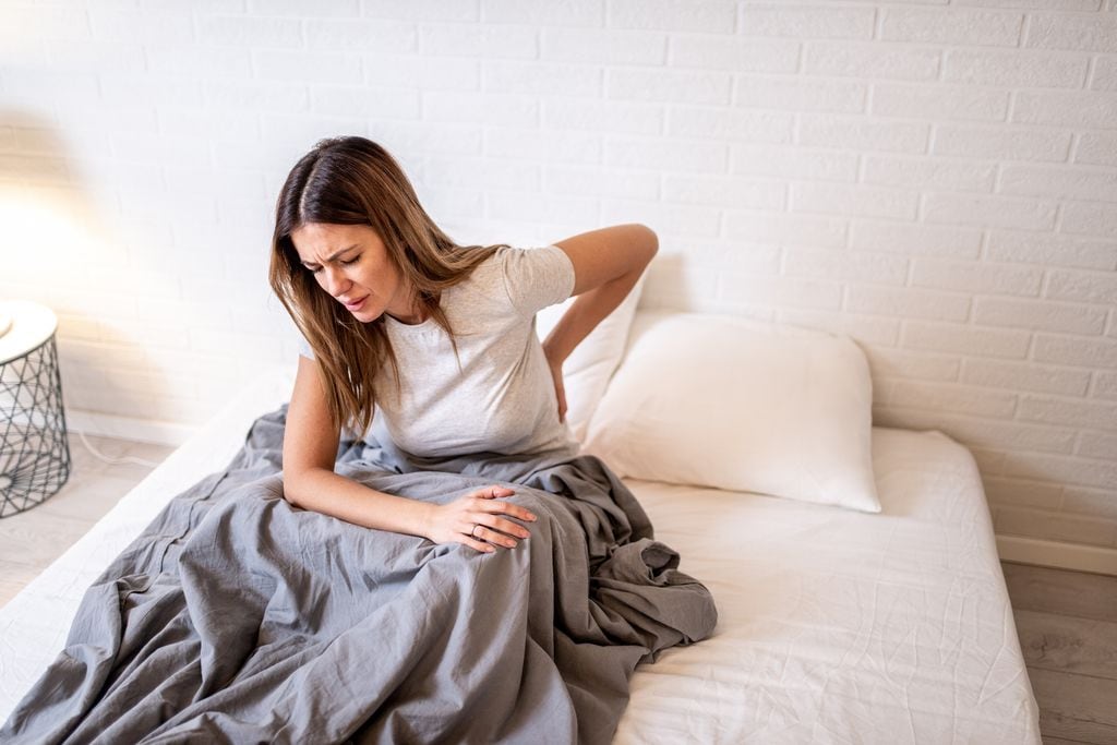 mujer con dolor de espalda en la cama