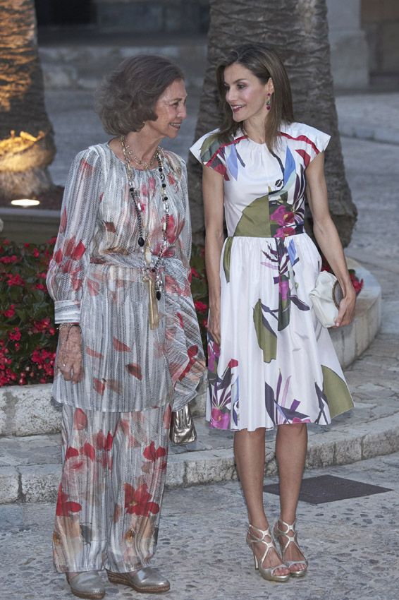 Para la ocasión doña Letizia estrenó un elegante vestido estampado de manga corta de Juan Vidal que combinó con unas de sus sandalias preferidas. Doña Sofía, por su parte, escogió un original conjunto de pantalón y casaca gris con detalles en rojol. En sus pies, unas cómodas alpargatas plateadas
