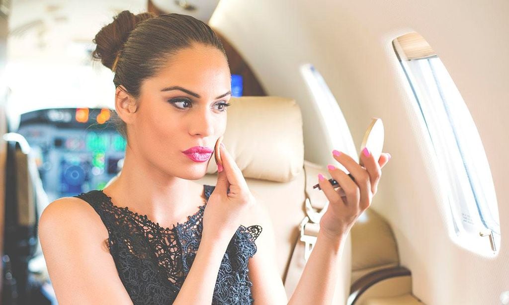 Mujer maquillándose durante un viaje en avión