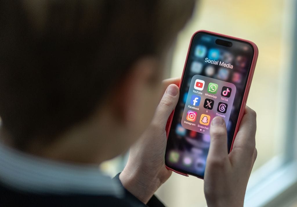 BATH, UNITED KINGDOM - FEBRUARY 25: In this photo illustration a a 12-year-old school boy looks at a iPhone screen A 12-year-old boy looks at an iPhone screen showing various social media apps including TikTok, Facebook and X on February 25, 2024 in Bath, England. This week the UK government issued new guidance backing headteachers in prohibiting the use of mobile phones throughout the school day, including at break times. Many schools around the country are already prohibiting mobile phone use over concerns. The amount of time children spend on screens each day rocketed during the Covid pandemic by more than 50 per cent, the equivalent of an extra hour and twenty minutes. Researchers say that unmoderated screen time can have long-lasting effects on a child's mental and physical health. Recently TikTok announced that every account belonging to a user below age 18 have a 60-minute daily screen time limit automatically set. (Photo by Matt Cardy/Getty Images)