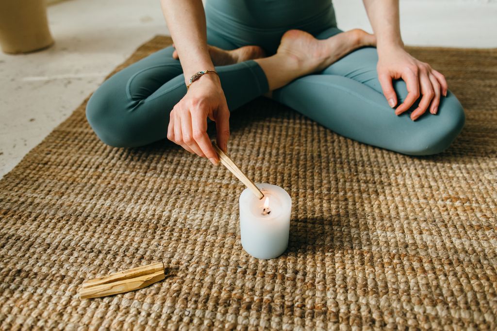 Una mujer quemando palo santo con una vela