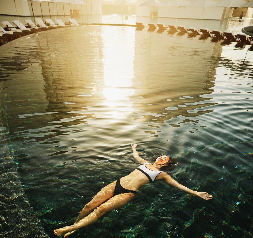 Mujer joven disfrutando de un baño en la piscina del hotel