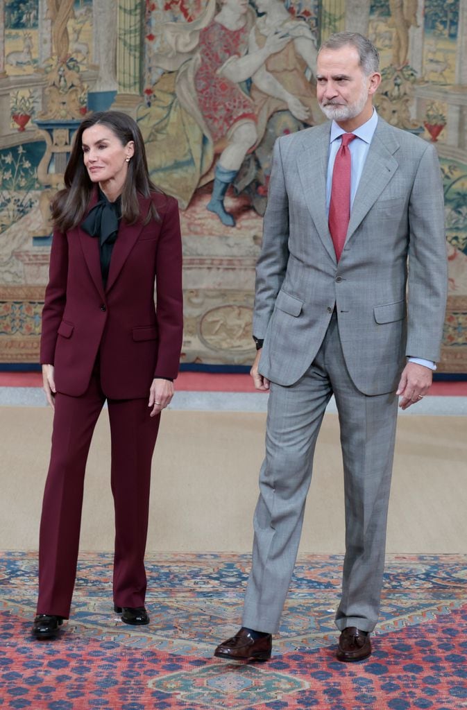 La reina Letizia con un traje burdeos y blusa de lazo