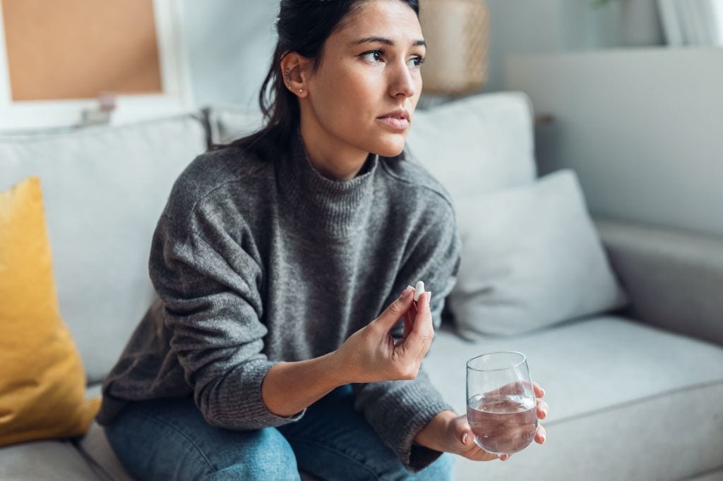 Mujer preocupada antes de tomar una pastilla