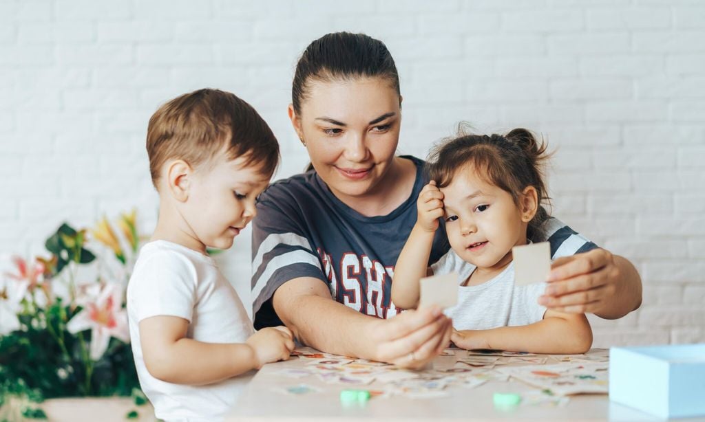 mother playing with her children at home in cards