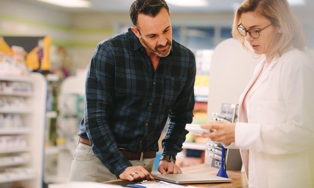 Pharmacist showing medicine to customer in pharmacy