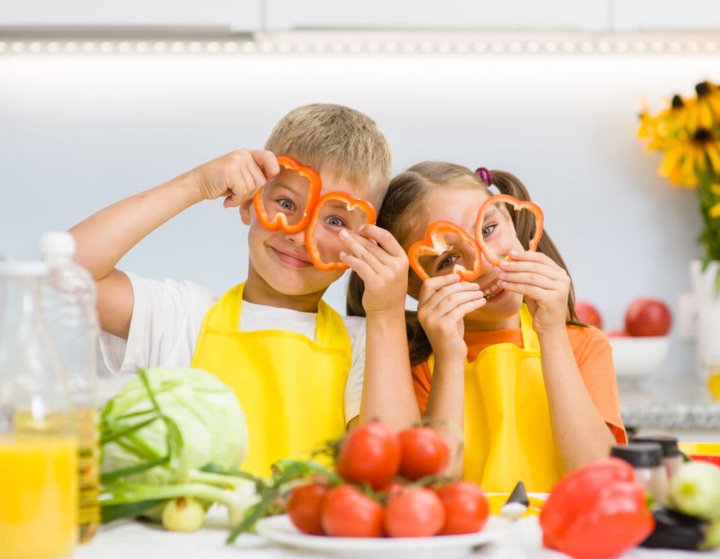 Niños en la cocina con pimientos en los ojos