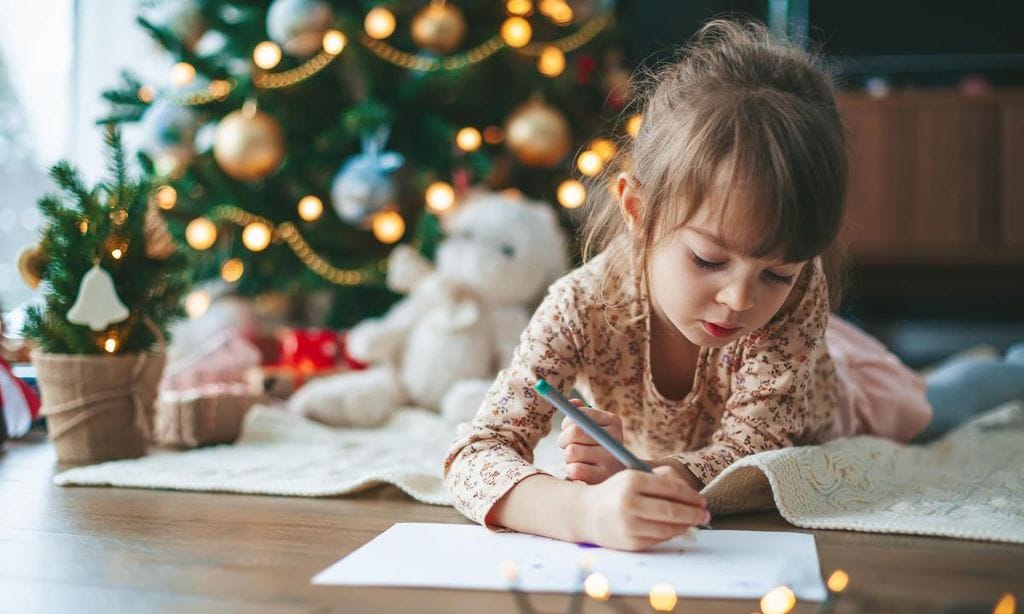 ni a escribiendo carta a los reyes magos al lado de rbol