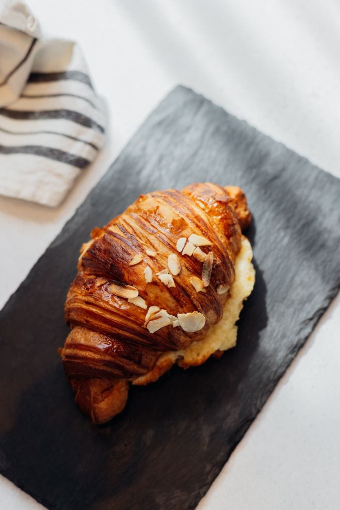 Fresh almond croissant on slate board on light table