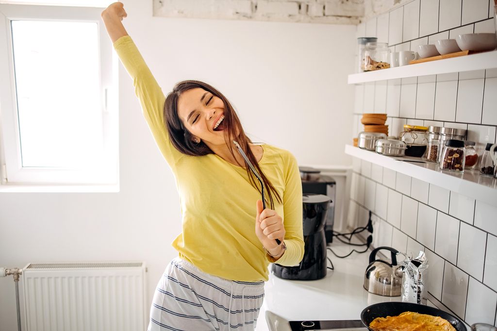 mujer feliz y alegre en la cocina, cantando