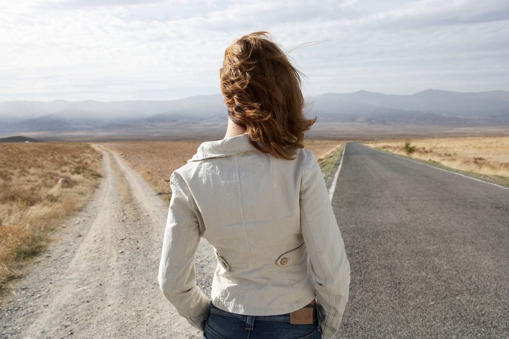 mujer mirando al horizonte, decidiendo entre dos caminos