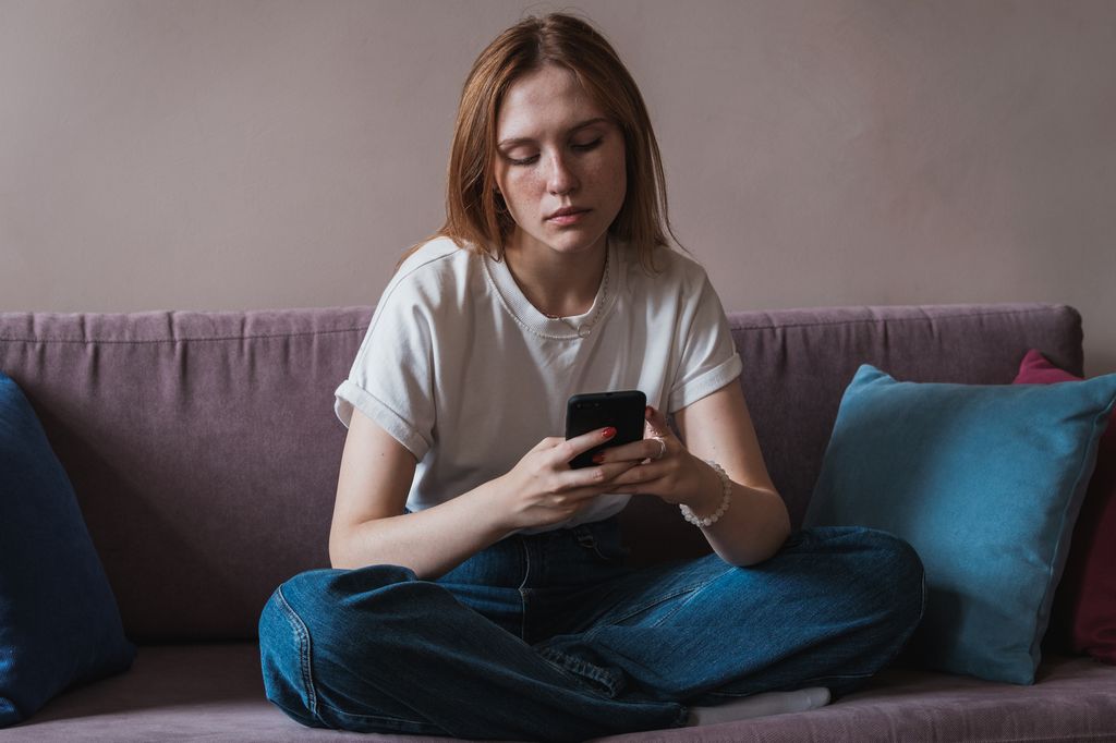 mujer joven seria mirando al móvil 