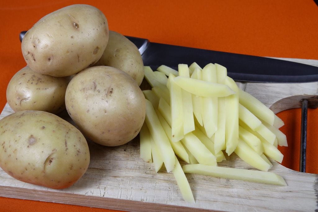 Una vez peladas las patatas y cortadas en bastones, hay que introducirlas en agua fría y un chorrito de vinagre.