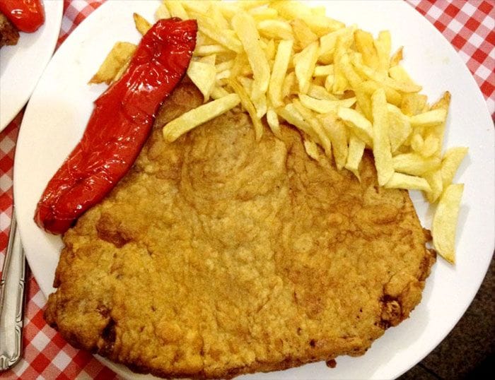 Normalmente el cachopo se acompaña con pimientos y patatas. El que vemos en la imagen es el que sirven en 'Hermanos Ordás', restauraurante que el año pasado ganó el 'Campeonato de Cachopos’ de la Comunidad de Madrid. 
